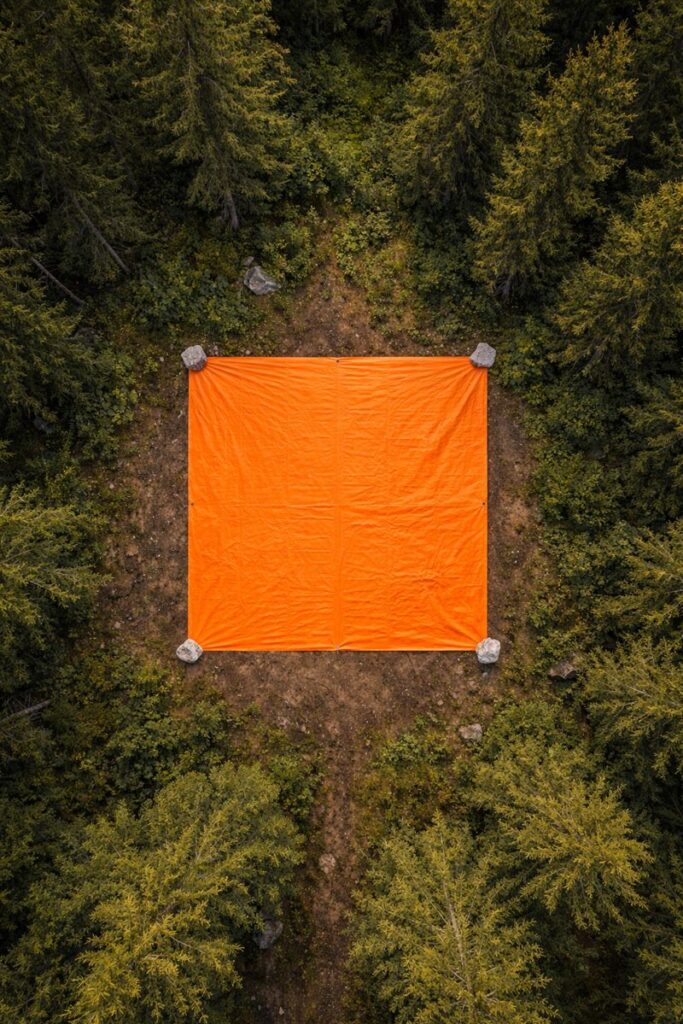 High-visibility orange tarp used as visual emergency signal in wilderness clearing